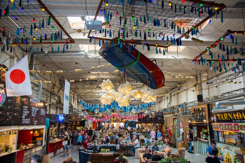 People meeting and sharing food in a colourful food hall in Helsingør.